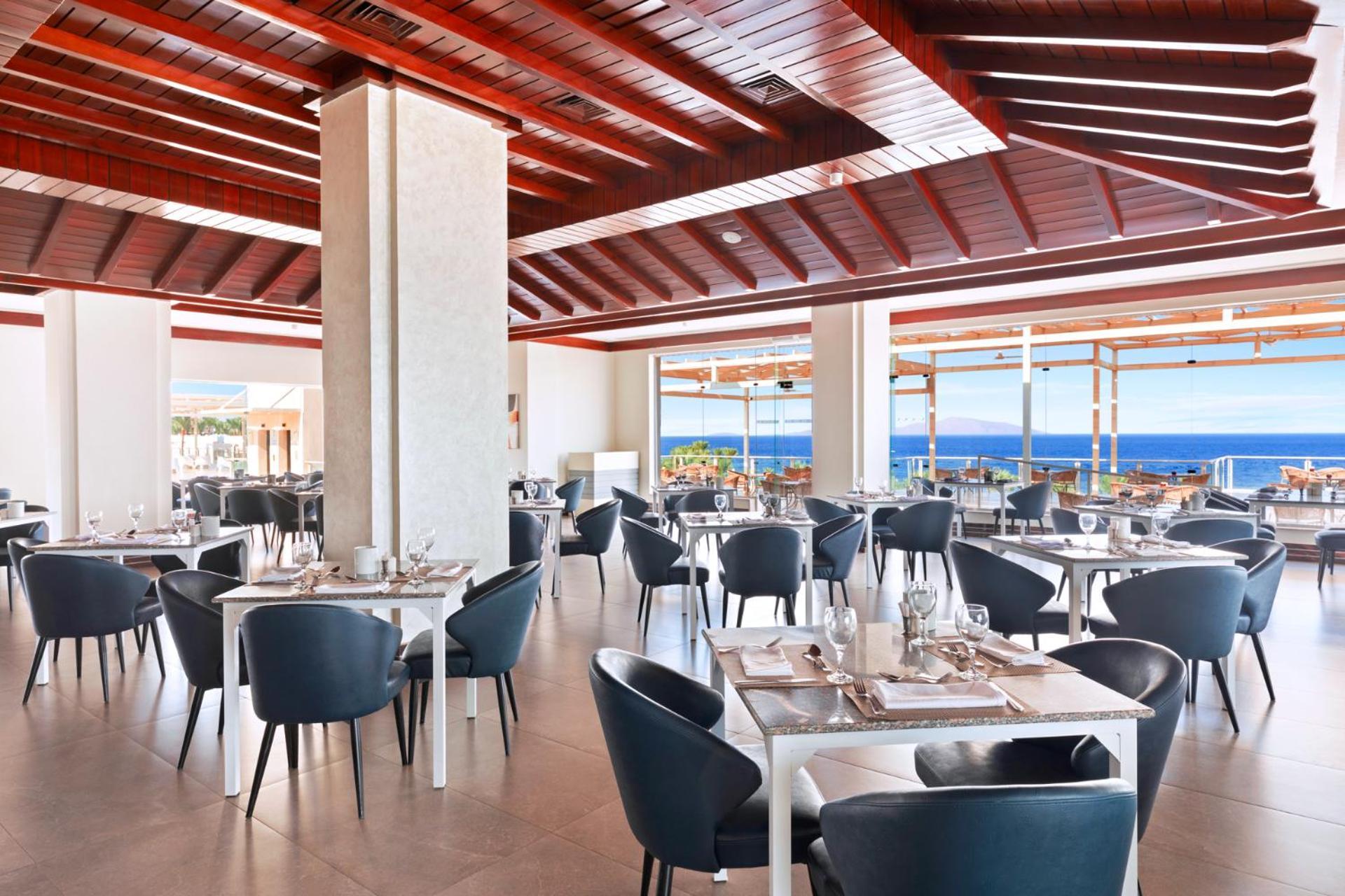 Pickalbatros Royal Grand Sharm - Adults Friendly 16 Years Plus ภายนอก รูปภาพ The photo shows a modern restaurant interior with a spacious and well-lit design. There are several tables set for dining, featuring white tablecloths and elegant dinnerware. The chairs are sleek and dark, contrasting with the bright surroundings. La
