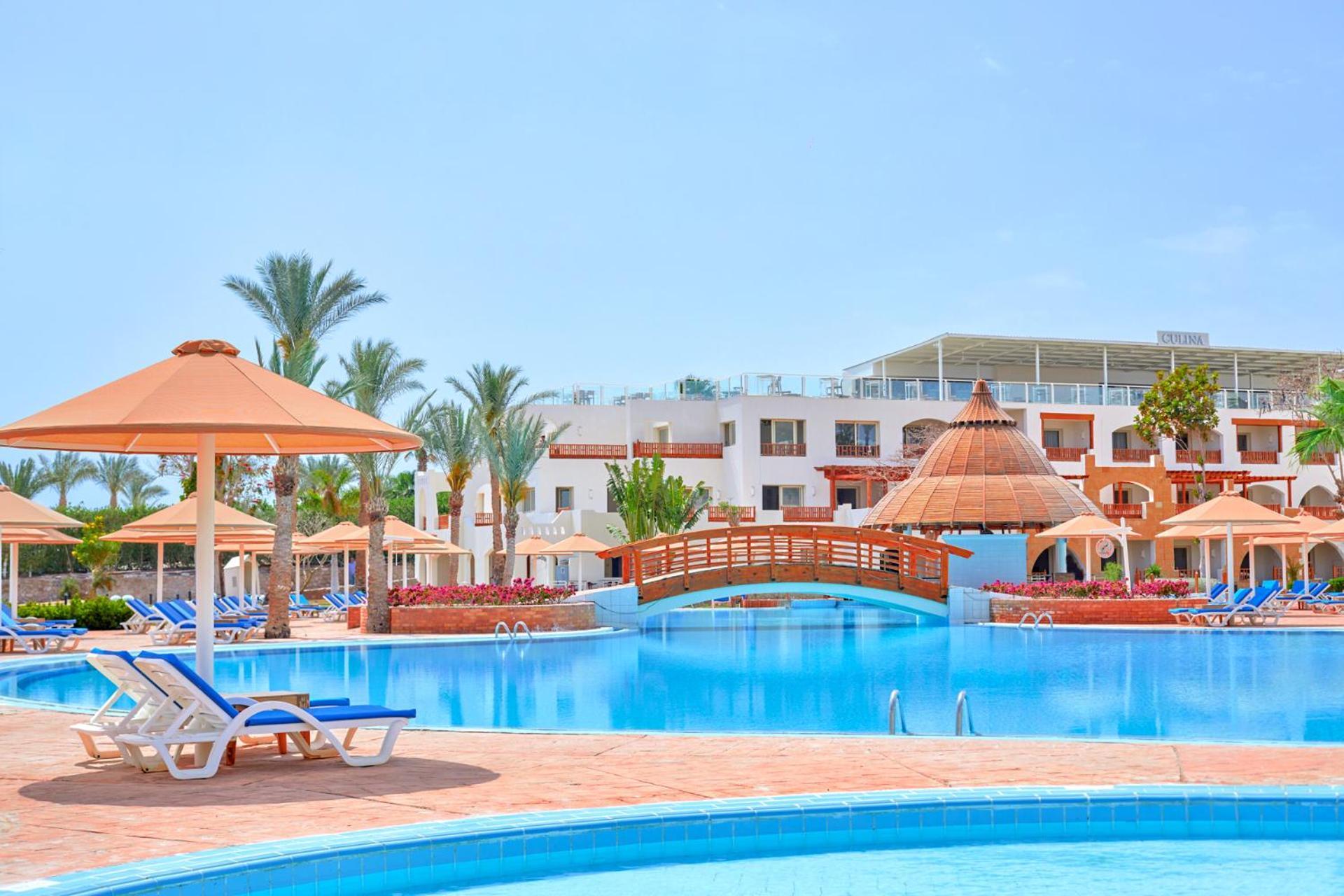 Pickalbatros Royal Grand Sharm - Adults Friendly 16 Years Plus ภายนอก รูปภาพ The photo depicts a beautiful resort setting featuring a large, inviting swimming pool. There are several lounge chairs positioned around the pool, along with straw umbrellas providing shade. In the background, there is a charming wooden bridge archi